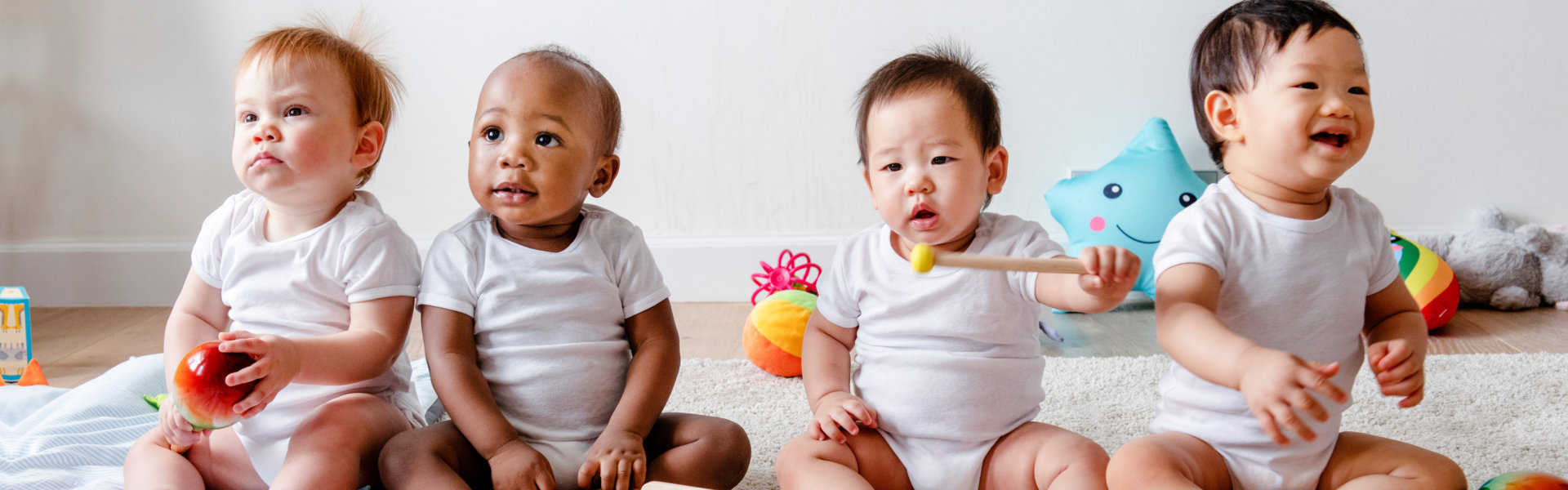 4 infants holding toys